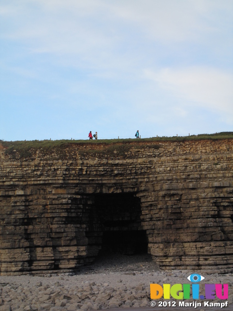 SX25199 People walking over cave in cliffs